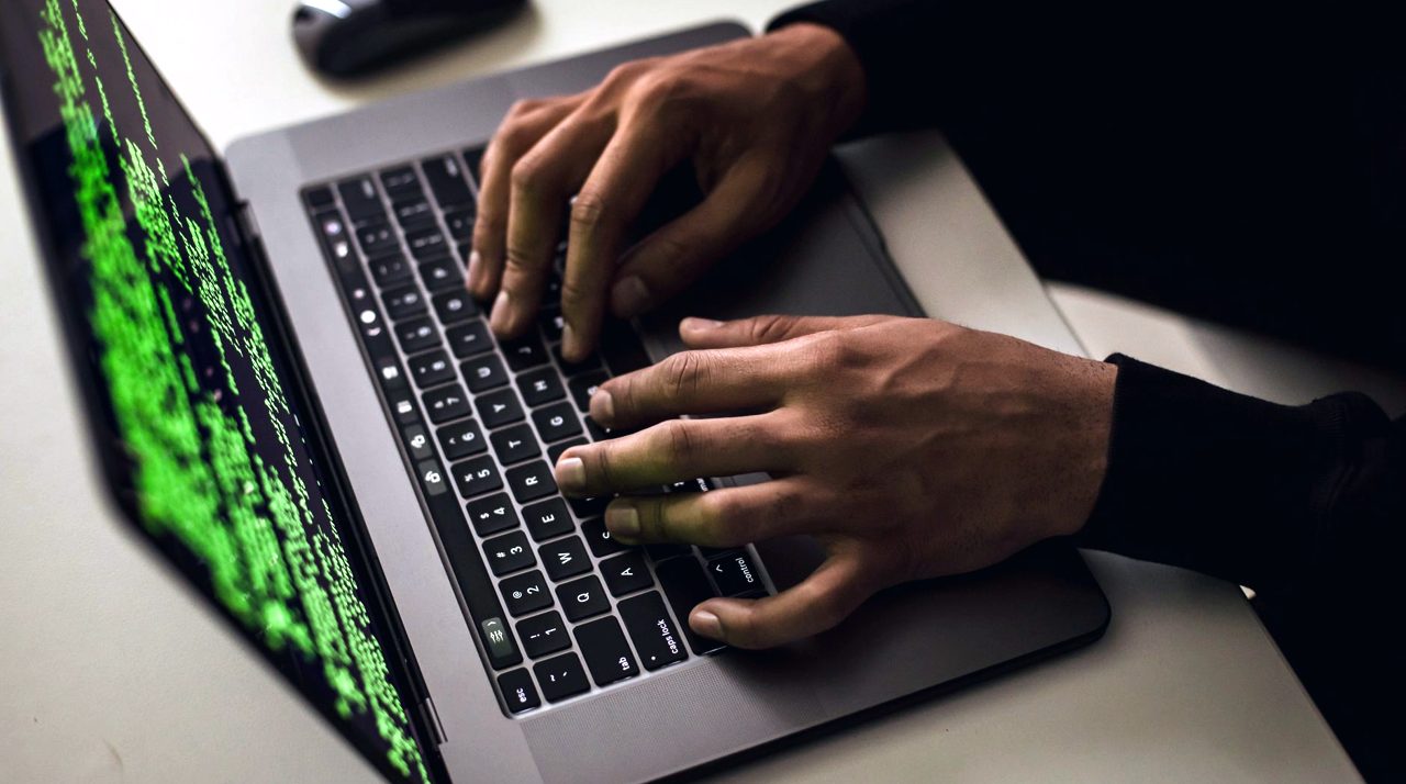 Mains sur un ordinateur portable, écran de code