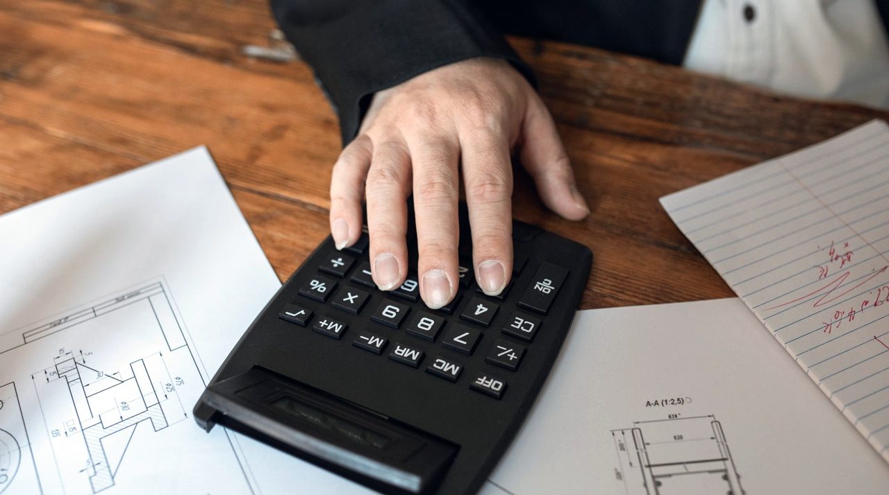 Main sur une calculatrice, documents étalés